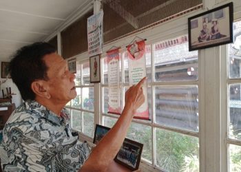 Drs Djomen Purba sedang menunjukkan foto penabalan Edwin Bingei Purba Siboro dengan istrinya boru Damanik. (foto : HTP)