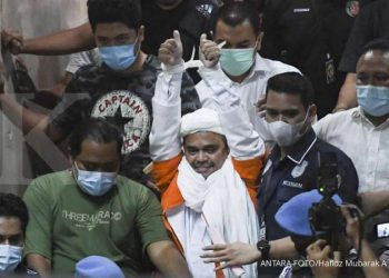 Rizieq Shihab berjalan menuju mobil tahanan usai diperiksa di Mapolda Metro Jaya, Jakarta, Minggu (13/12/2020) dini hari.
