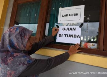 ILUSTRASI. Guru menempelkan famflet penundaan UNBK di SMK Negeri 1 Serang, Banten, Senin (16/3/2020).