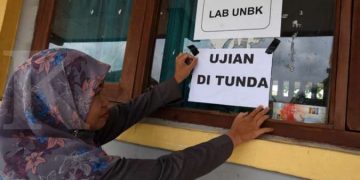 ILUSTRASI. Guru menempelkan famflet penundaan UNBK di SMK Negeri 1 Serang, Banten, Senin (16/3/2020).